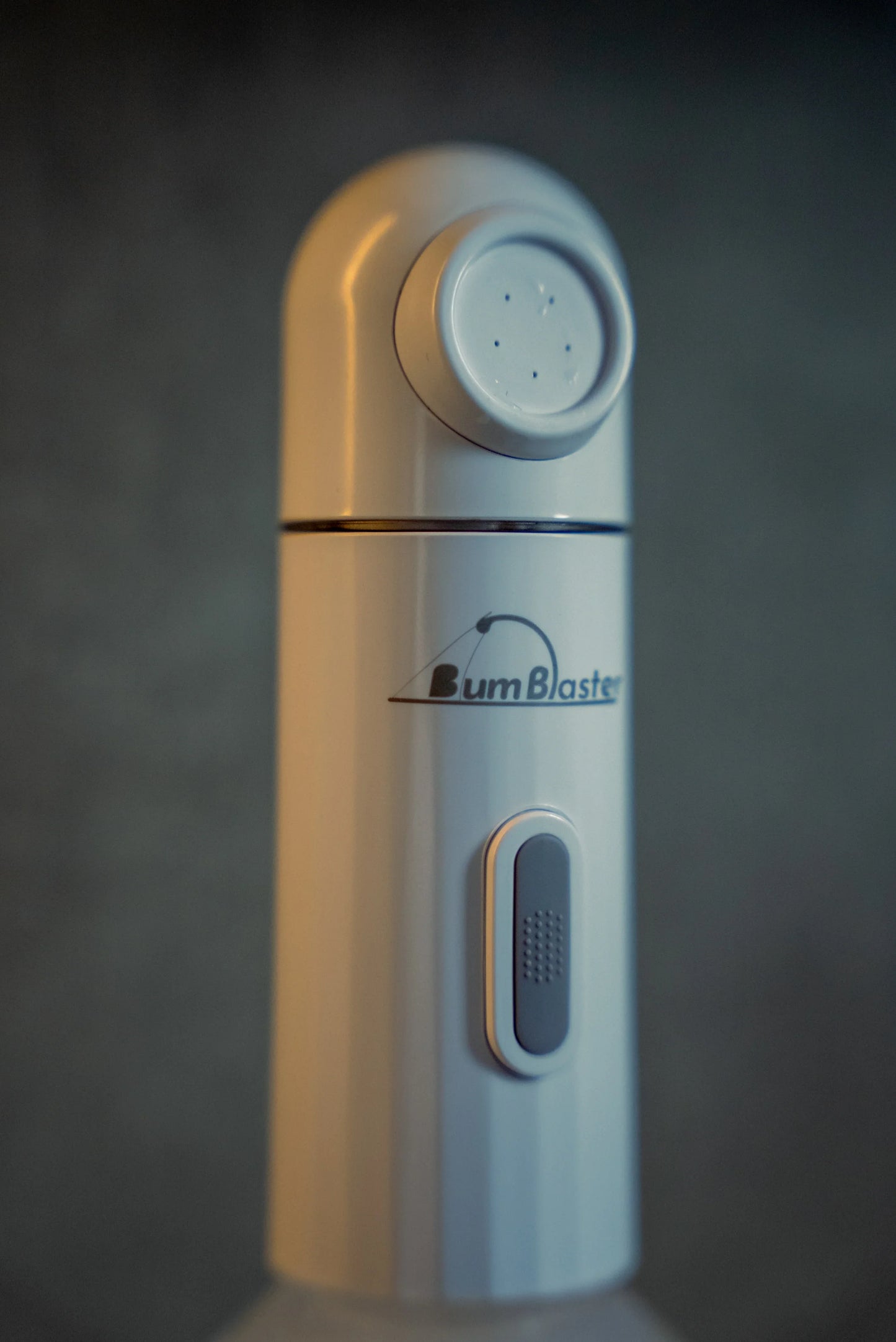 Close-up of a white BumBlaster portable bidet with nozzle and power button